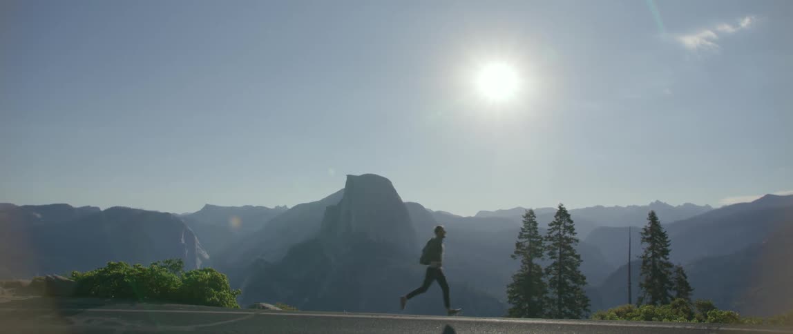 Man runs down road with mist covered mountain range in background