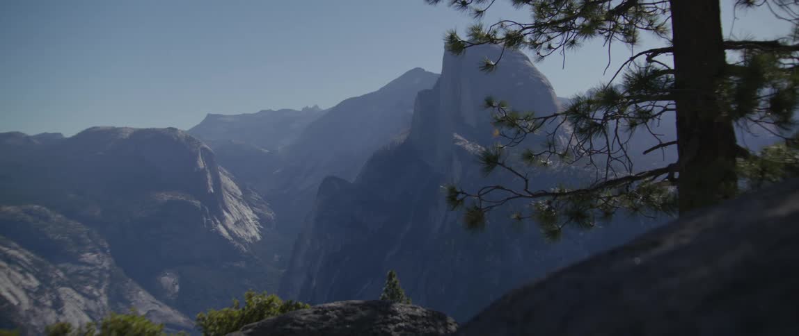 View from a mountain ledge of a mountain range under a hazy sky