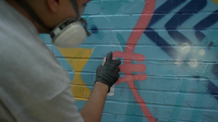 A man is spray painting a brick wall