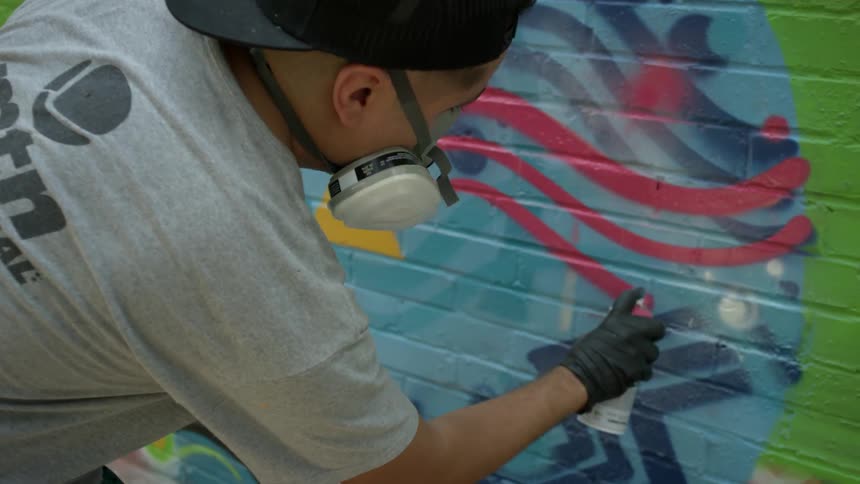 A person spray paints a wall