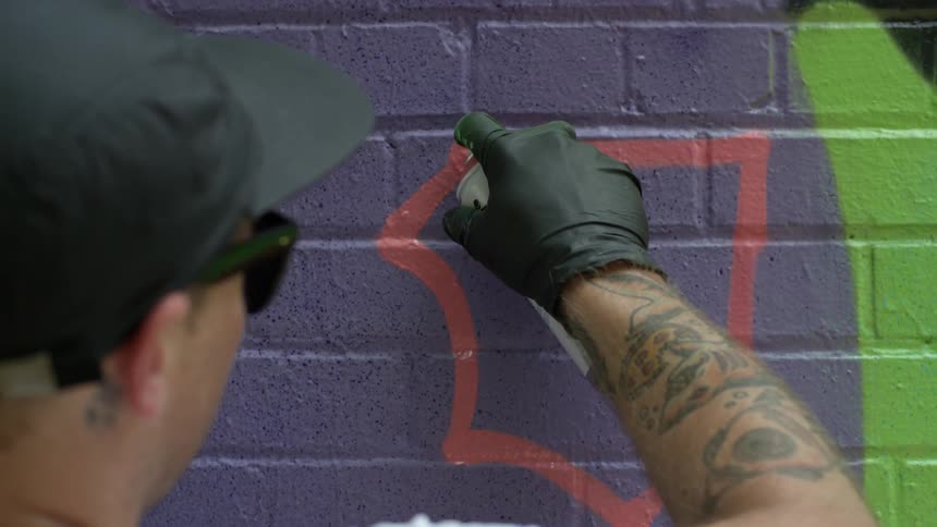 A man is spraying an image on a brick wall