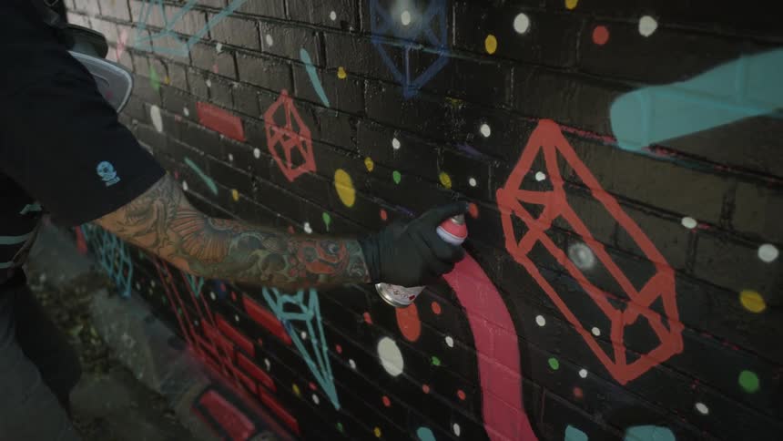 A man uses spray paint to create art on a building