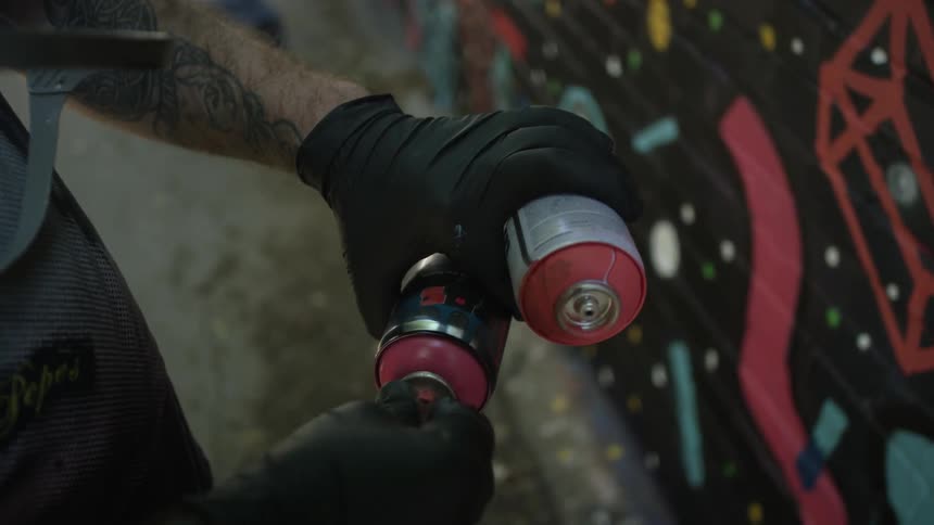 A man adjusts a couple of cans of spray paint