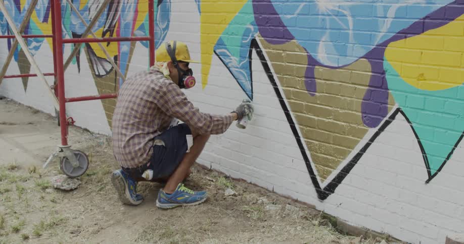 A person spray paints the wall