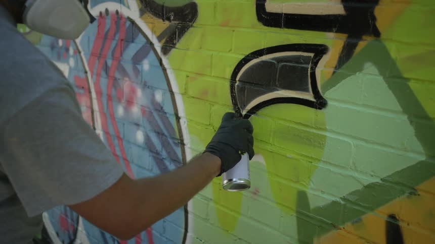A man is spray painting on a brick wall