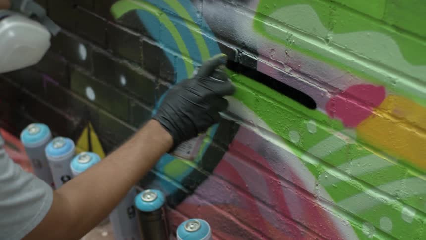 A man is spray painting on a brick wall