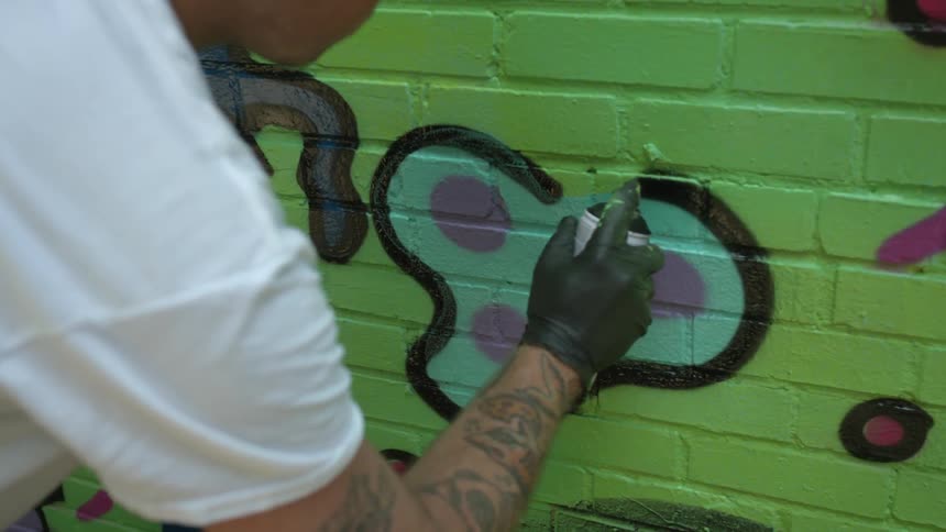 A person spray paints a wall