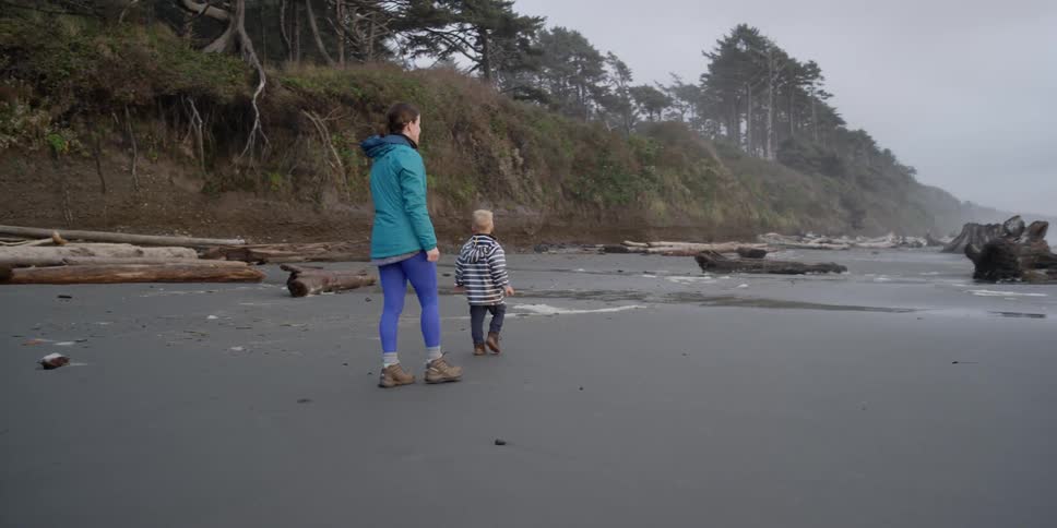 A woman and boy walk along the beach