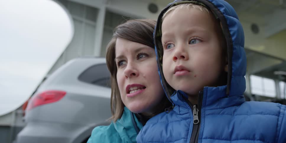 A woman talks to her child near a vehicle