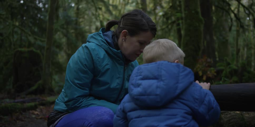 A woman is crouching near a boy talking