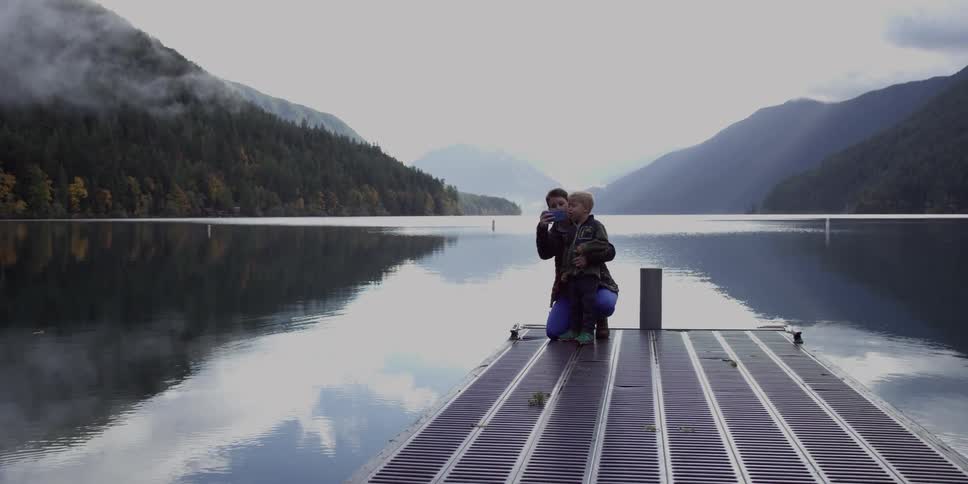 A woman crouches down with a boy on a pier