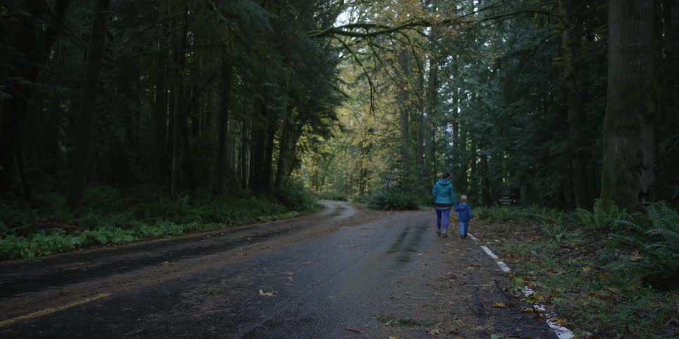A woman and child walk down an empty road