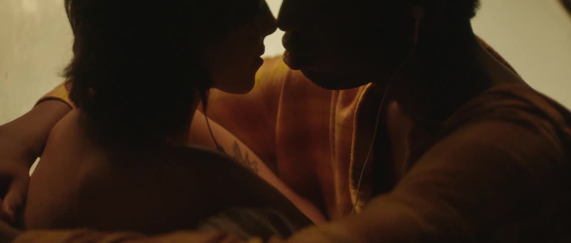 A couple are sitting together hugging and kissing
