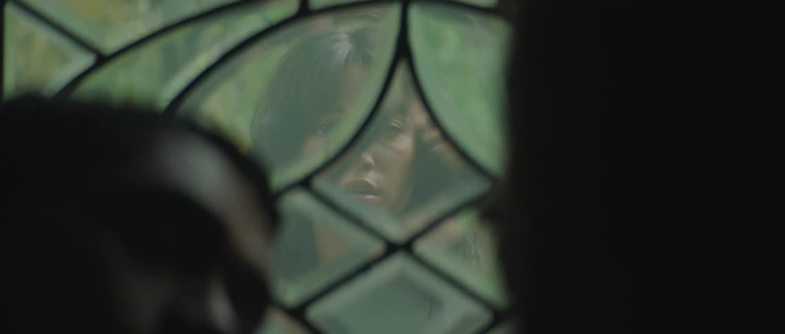 A womans jaw drops as she stands outside a window and sees two people kissing