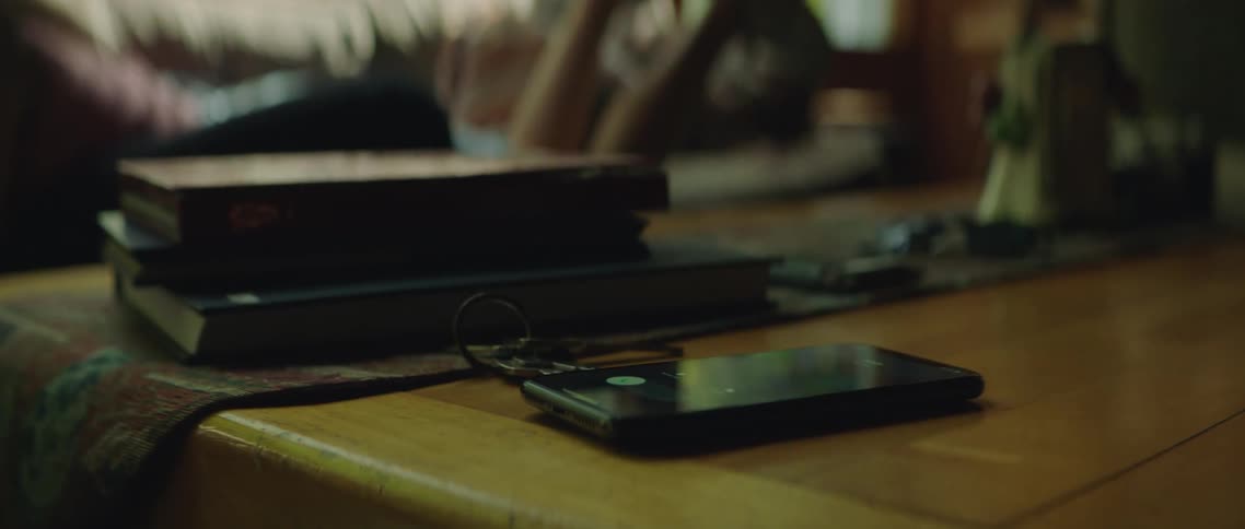 Smartphone ringing on the coffee table in the living room next to a woman laying on the couch