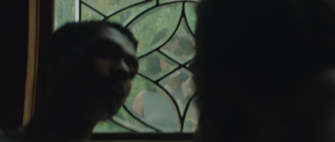 A woman watches a couple kiss from the window