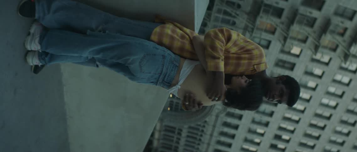 Young couple lovingly hugging over the rooftop of a building at evening