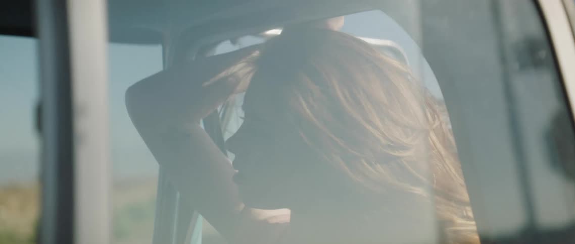 A woman sitting in a car in a rural area