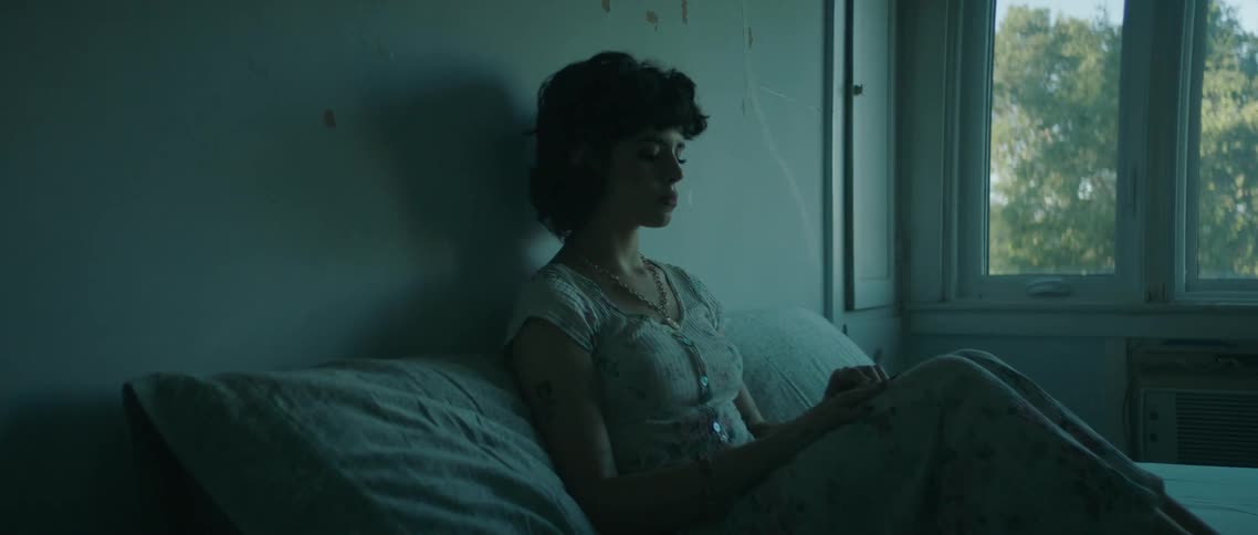A woman sits in bed with her eyes closed