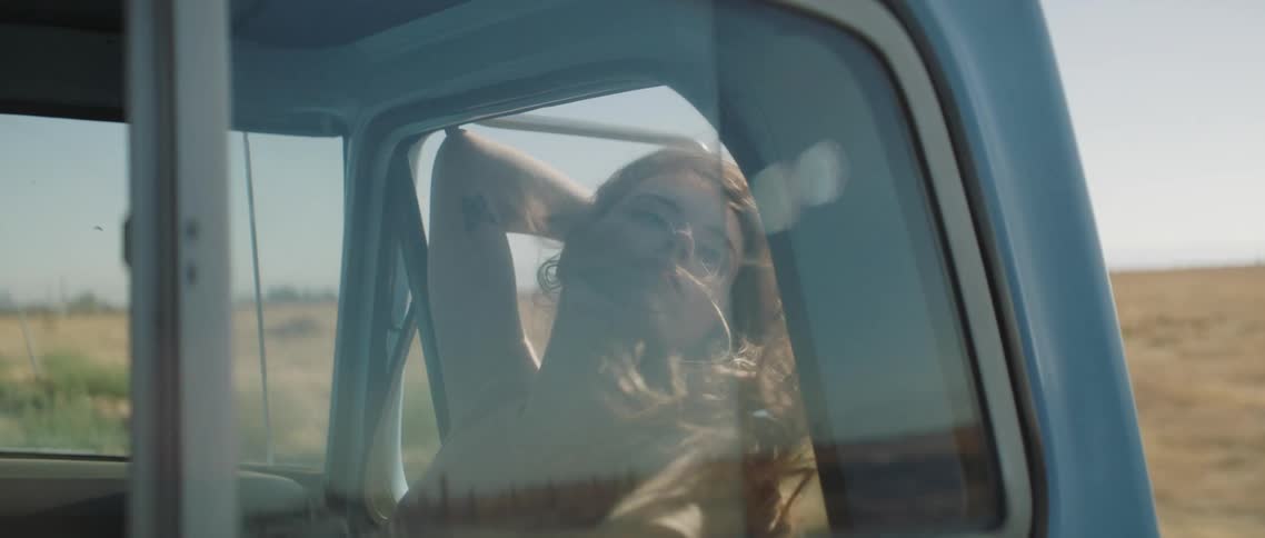 Blonde woman sitting on the passanger seat of a car driving on a rural road