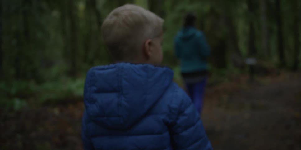 A woman and her son walking in the forest