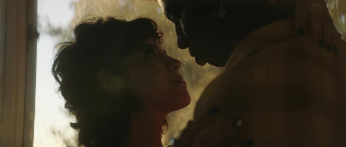 Couple slow dance together near window gazing into each others eyes