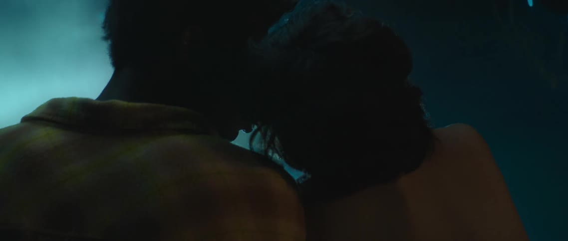 A young couple sit close and lean in for a kiss while outdoors at nighttime