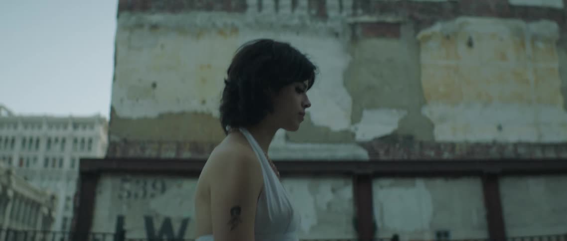 Young woman wearing a white dress walks away from a man on the street of the city at morning