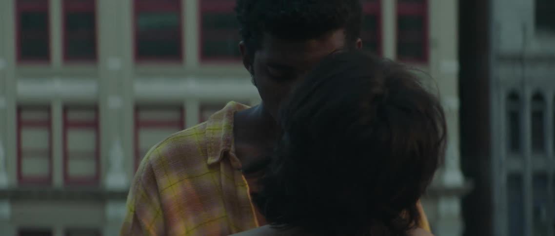 Young couple kissing on the roof top of a building in the city at sunset
