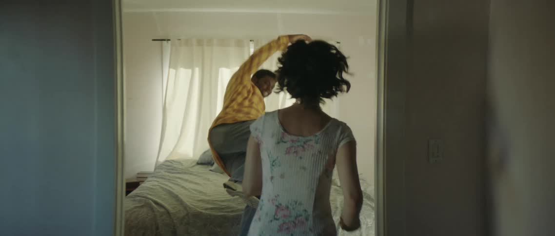 Two people running and jumping onto a bed