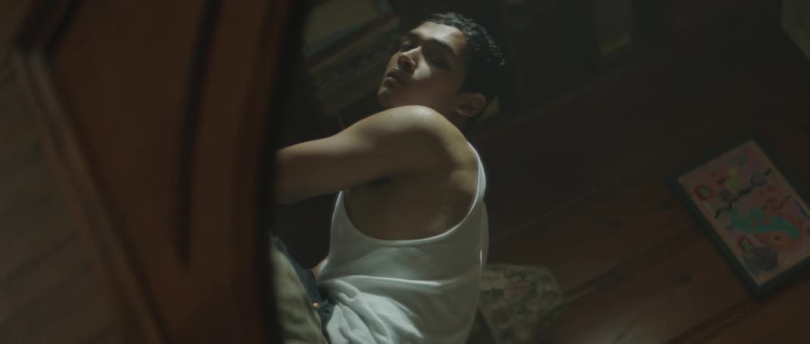 Reflection on a mirror of a young man sitting on a bed