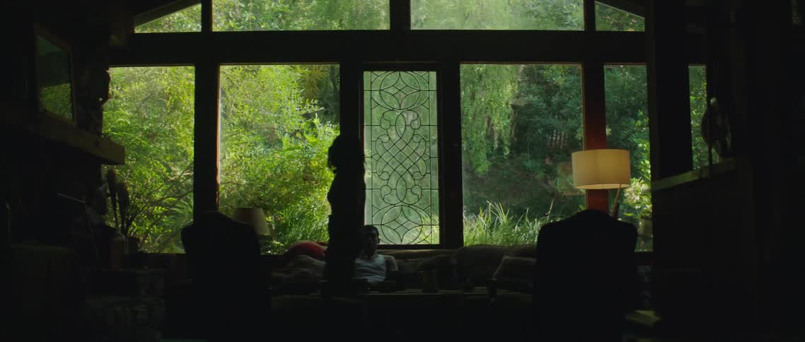 A woman yells at her boyfriend on the couch while pacing back and forth