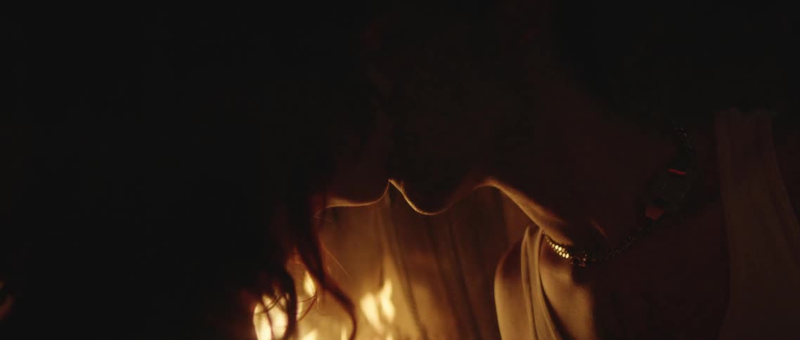 Couple kiss then sit back lit by fire in fireplace