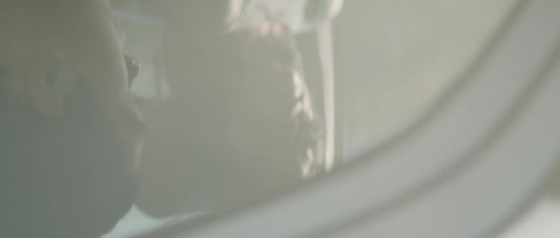A young man and woman ride in a car as the camera spirals just outside of the driver side window