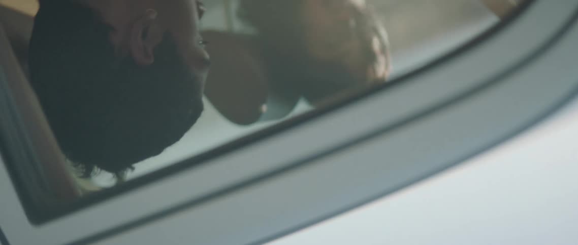 Spinning footage of a young couple sitting on a car on a rural road surrounded by smoke at sunset