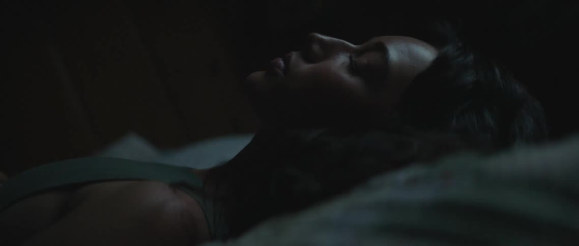 Profile of a young woman resting in bed inside a dark room at night