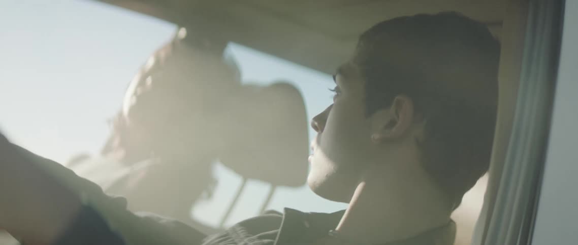Twisting footage of a couple sitting on a car surrounded by smoke at sunset