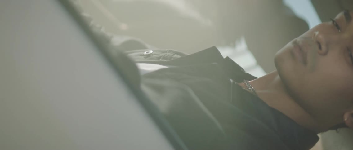 A man is sitting inside a static car and is looking outside the window