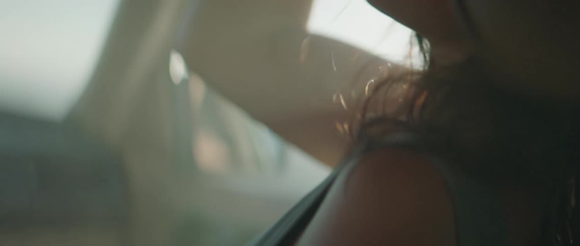 A woman leans back in her car seat as smoke and dust through the passenger side window