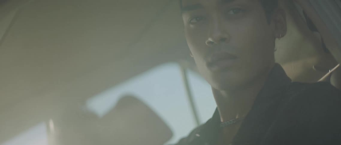 A man is sitting inside a car and is looking outside the window