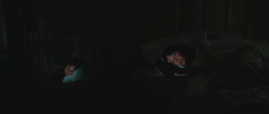 A woman laying in a bed looking at a phone