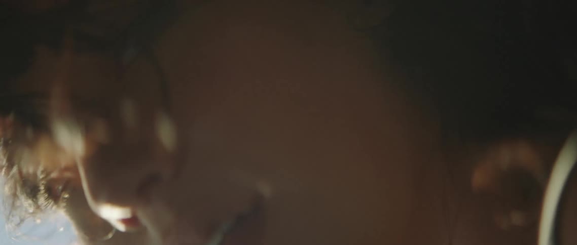 The wind blows a womans hair as she leans out a car window