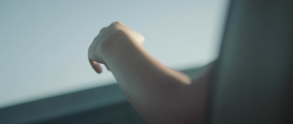 Waving of a young woman hand sitting inside a car at sunset