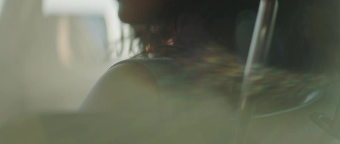 A females hair blows in a breeze as she sits in a vehicle