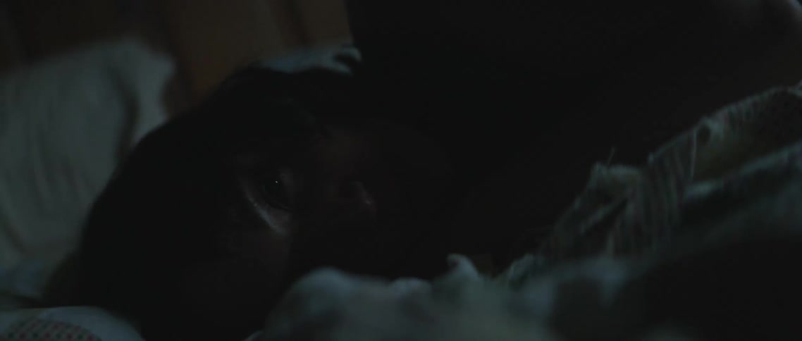 A woman is resting in bed with her eyes open