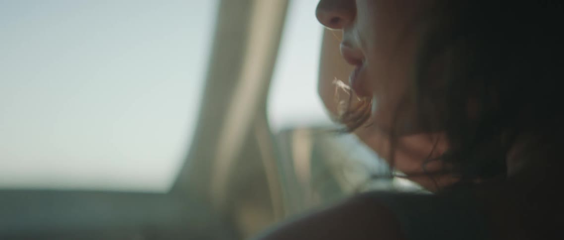 A woman in a vehicle with smoke with the sky and clouds in the background