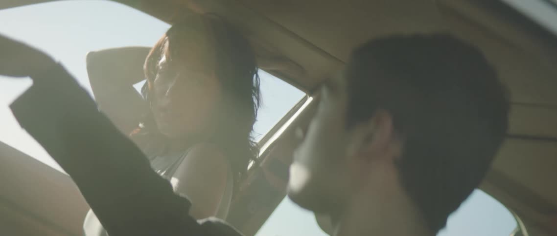 Two people sitting in a car as the camera orbits