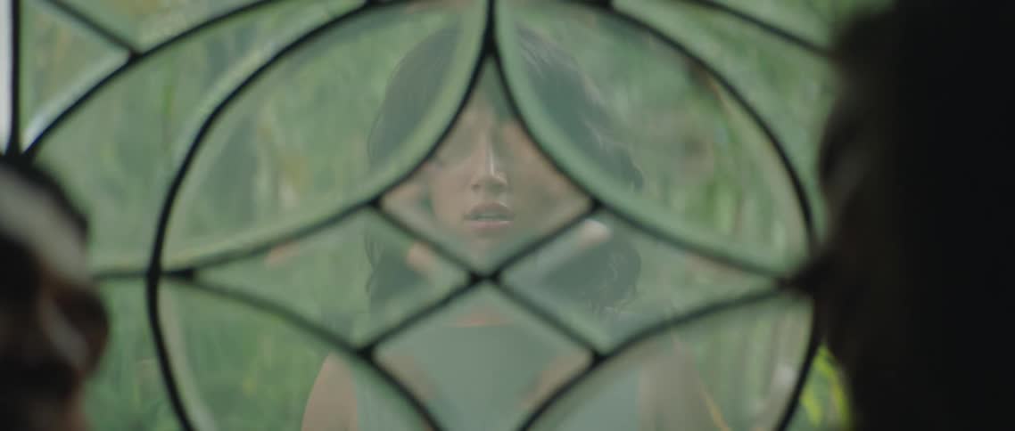 A woman stands outside a window and stares as she watches two people kissing inside