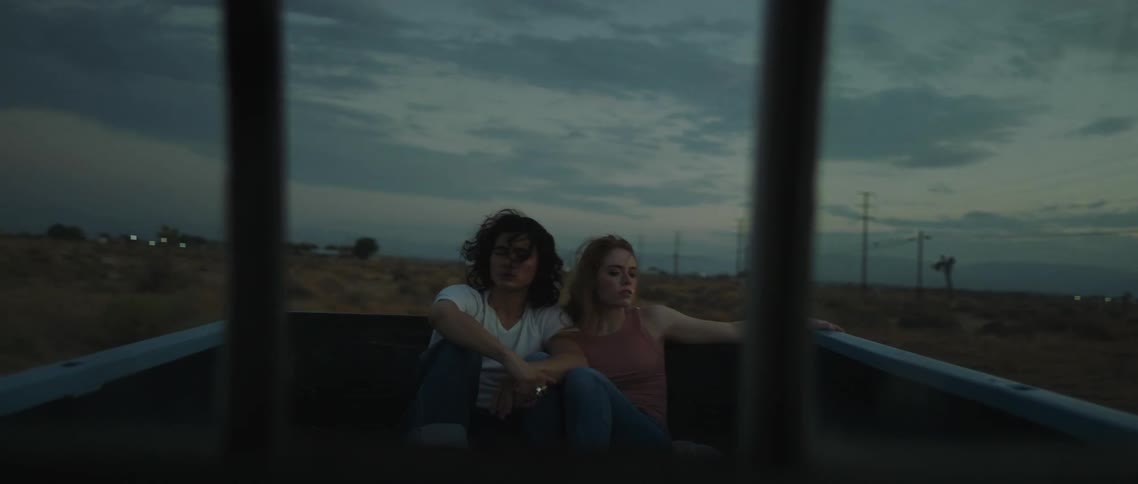 A man and woman riding in the back of a truck outdoors