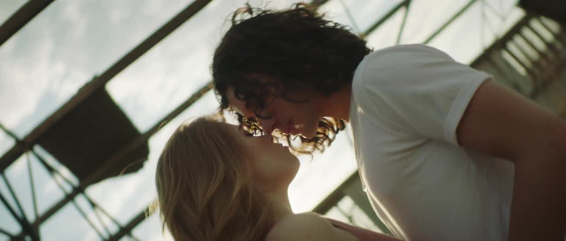 Young couple kissing inside an abandoned warehouse hangar at sunset